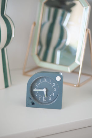 Stylish clock on a shelf with decorative mirror