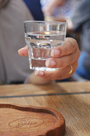 Hand holding a glass of water in a casual setting