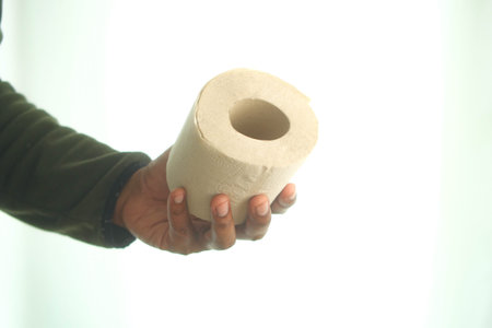 Holding a toilet paper roll against a light background