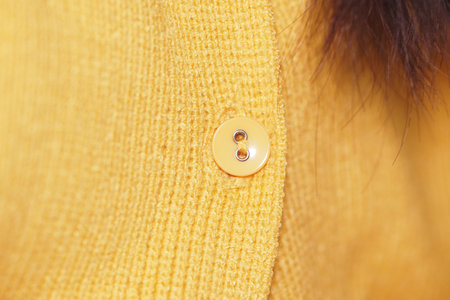 Close-up view of a yellow button on cozy fabric
