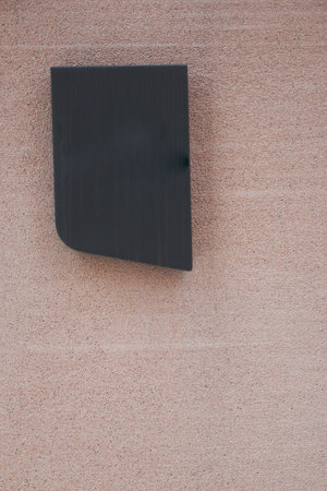 Black metal box on a light pink wall in outdoor setting