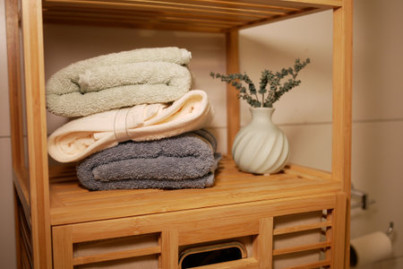 Soft towels and a vase on a wooden shelf in a bathroomの写真素材
