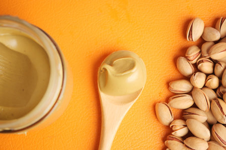 Creamy pistachio spread with nuts on orange background