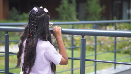Girl with braided hair looking over the railing in parkの写真素材