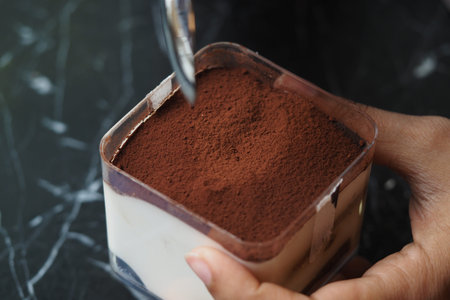 Preparing a delicious dessert with cocoa powder toppingの写真素材