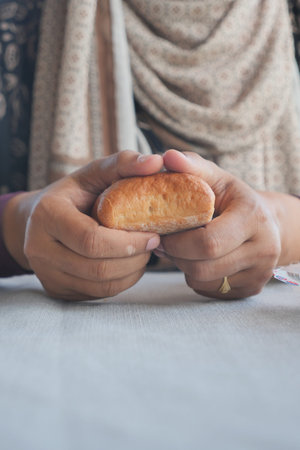 Hands holding a warm baked good at a cozy table setting