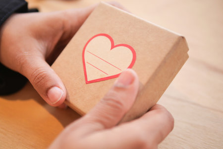 Gift box held in hands with a heart designの写真素材