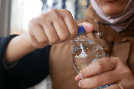 Person opening a water bottle indoorsの写真素材