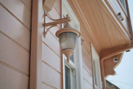 Vintage wall lamp on pink house exterior in daylightの写真素材