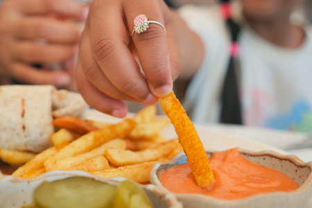 Kid enjoys dipping a crispy fry in a tasty sauce