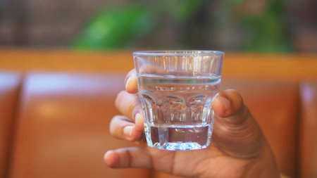 Glass of clear water being held in a cozy setting