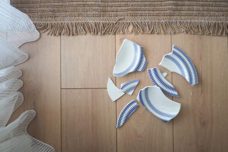 Broken porcelain pieces scattered on wooden floorの写真素材