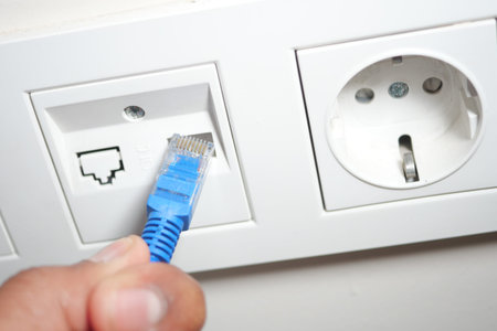 Connecting a blue Ethernet cable to a wall port in a home