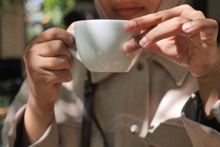 Woman Enjoying a warm beverage in a cozy cafe settingの写真素材