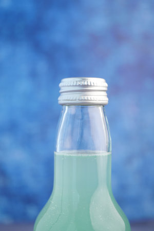 Refreshing green beverage in glass bottle on blue backgroundの写真素材
