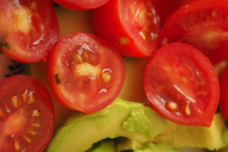Tomatoes and avocado slices on a sunlit plateの写真素材
