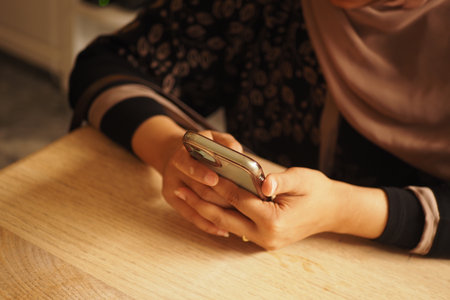 Person using smartphone at home in cozy settingの写真素材