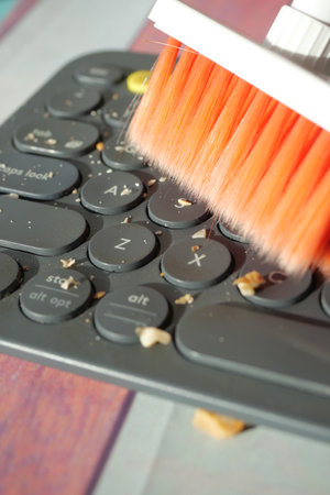 Cleaning debris from a computer keyboard with a brushの写真素材