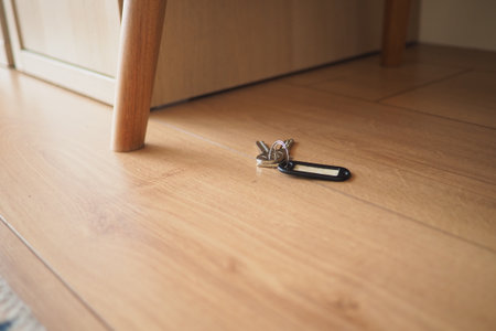 Keys are dropped on the wooden floor near a tableの写真素材