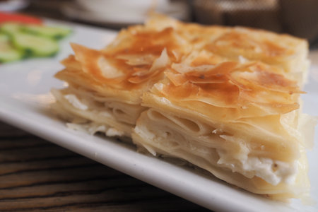 Delicious layers of turkish borek served with fresh vegetablesの写真素材