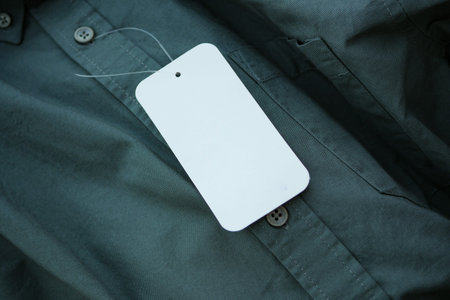 Shirt with blank tag resting on green fabric background