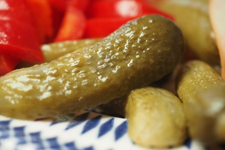 Fresh pickles and red peppers on a vibrant plateの写真素材