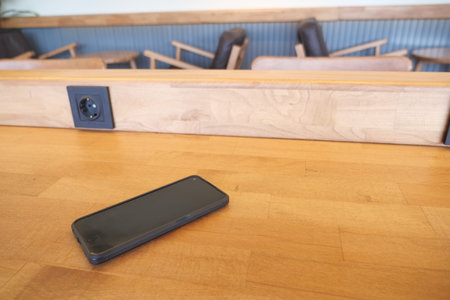 Smartphone resting on a wooden table in a cafe setting. lost smart phone concept