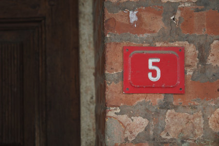 Bright red house number on a brick wall outside a doorの写真素材