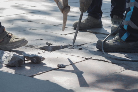 Workers repairing damaged pavement in a busy areaの写真素材