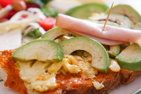 Freshly made sandwich topped with avocado and hamの写真素材