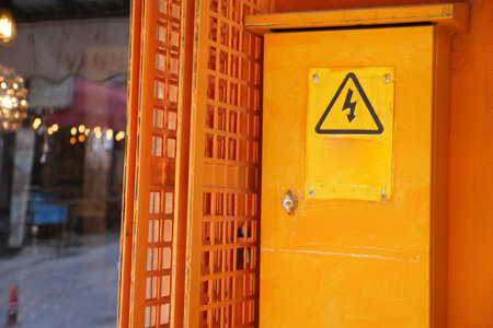 Electric warning sign on a bright orange box in the streetの写真素材