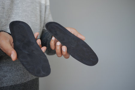 Person holds black insoles in a simple setting indoorsの写真素材