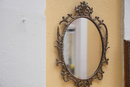 Ornate mirror hanging on a yellow wall with vintage style