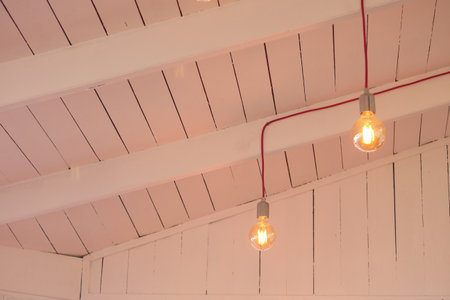 Light bulbs hanging from a bright wooden ceilingの写真素材
