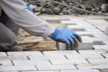 Worker laying bricks on a construction site for pavementの写真素材