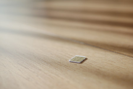 Small sim card on wooden surface in bright light. lost sim card conceptの写真素材