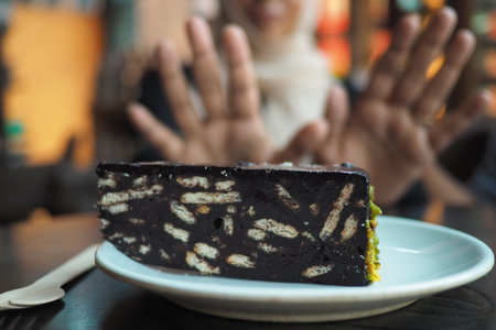 A dark chocolate dessert on a plate and a woman show no sign in background.