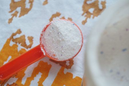 Scoop of laundry detergent on a vibrant fabric background