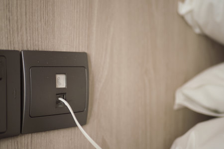 Charging device connected to wall socket near bedの写真素材