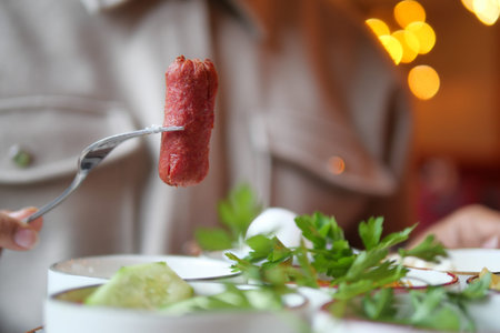 Delicious sausage on a fork at a cozy restaurant setting