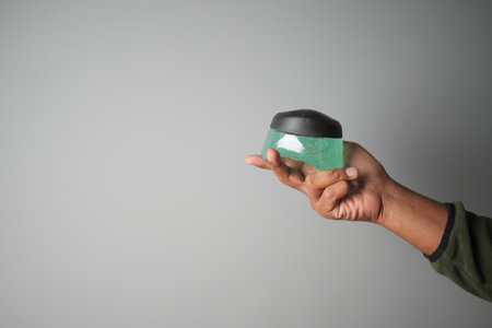 Holding a hair gel container on gray backgroundの写真素材