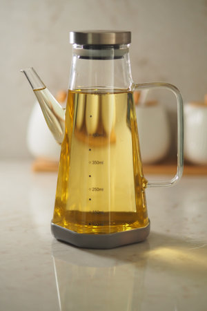 Glass oil dispenser on kitchen counter with herbsの写真素材