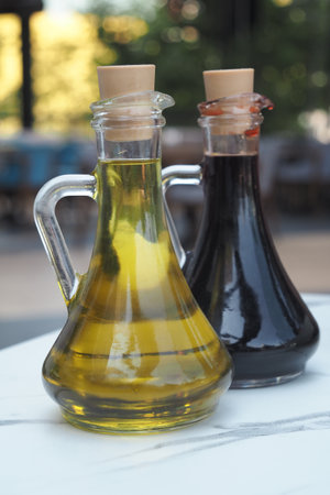 Oil and vinegar in glass bottles on a table outdoorsの写真素材