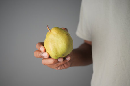 Holding a fresh green pear in a simple settingの写真素材