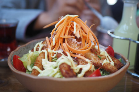 Fresh salad topped with carrots and fried chicken stripsの写真素材