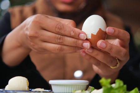 Cracking a soft boiled egg at a cozy kitchen tableの写真素材