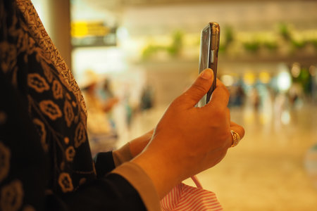 Woman using smartphone in a busy airport terminalの写真素材