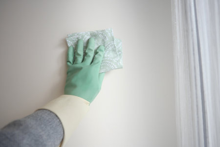 Cleaning a wall with gloves in a bright roomの写真素材