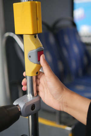 Person pressing stop button on city bus during ride