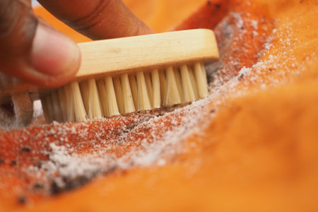 Cleaning a vibrant orange fabric with a brushの写真素材